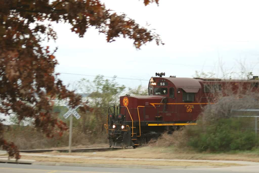 Red train running through trees on the Arkansas-Missouri Railroad, one of the best Arkansas train rides