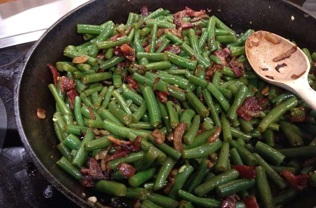 Arkansas green beans in a frying pan with a white spoon