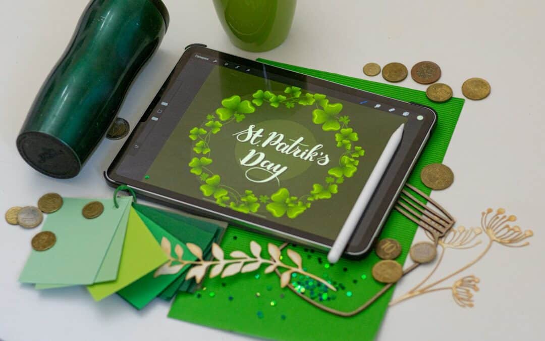 Green paper, black tablet, and St. Patrick's Day craft objects on a white background