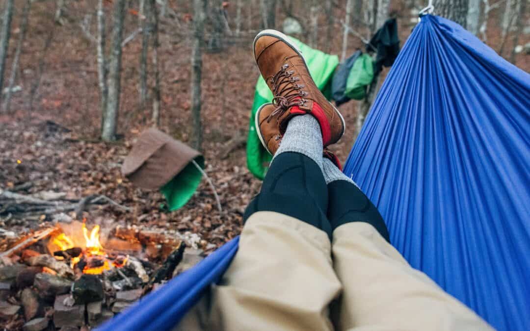 Camper in hiking boots resting in a blue hammock in the forest in Arkansas campsites