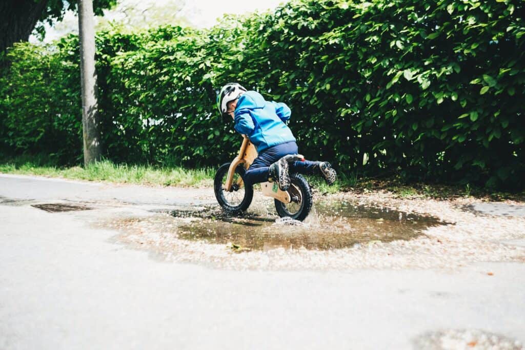 boy riding on bicycle during daytime through a mud puddle one of the basic life skills all children should learn